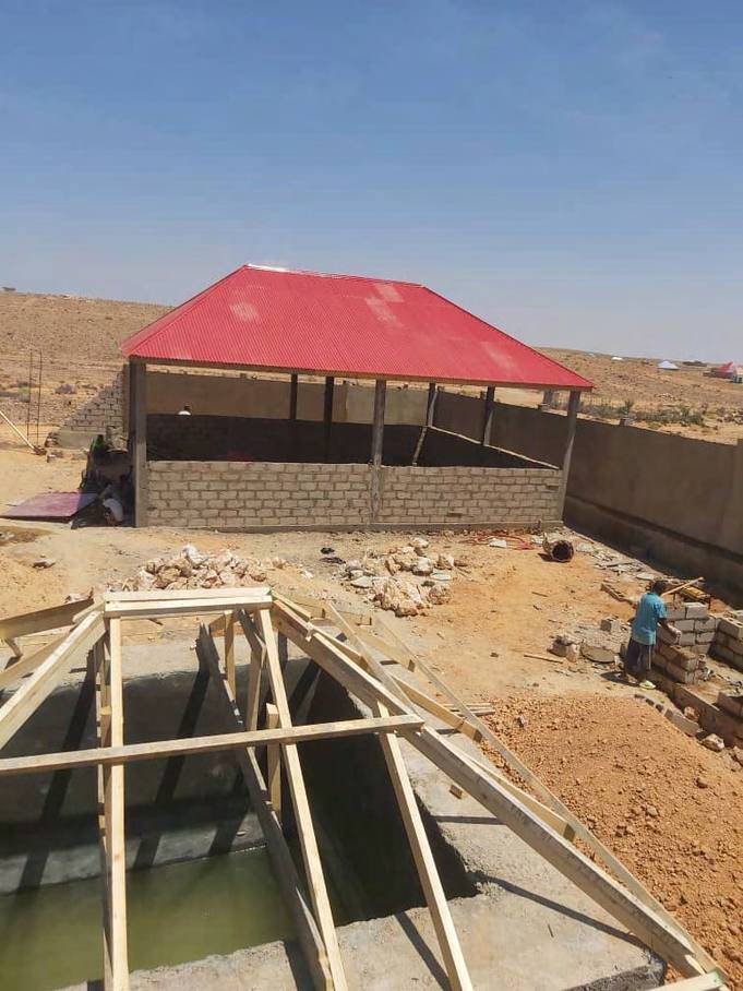 Masonry building under construction beside a formed underground water tank