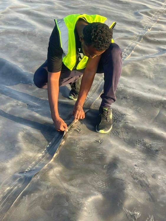 Worker fixing geomembrane liner inside a water reservoir