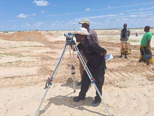 Surveyor taking levels with a tripod-mounted instrument
