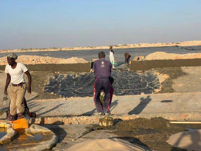 Workers fixing liner sheets across the floor of a water pan